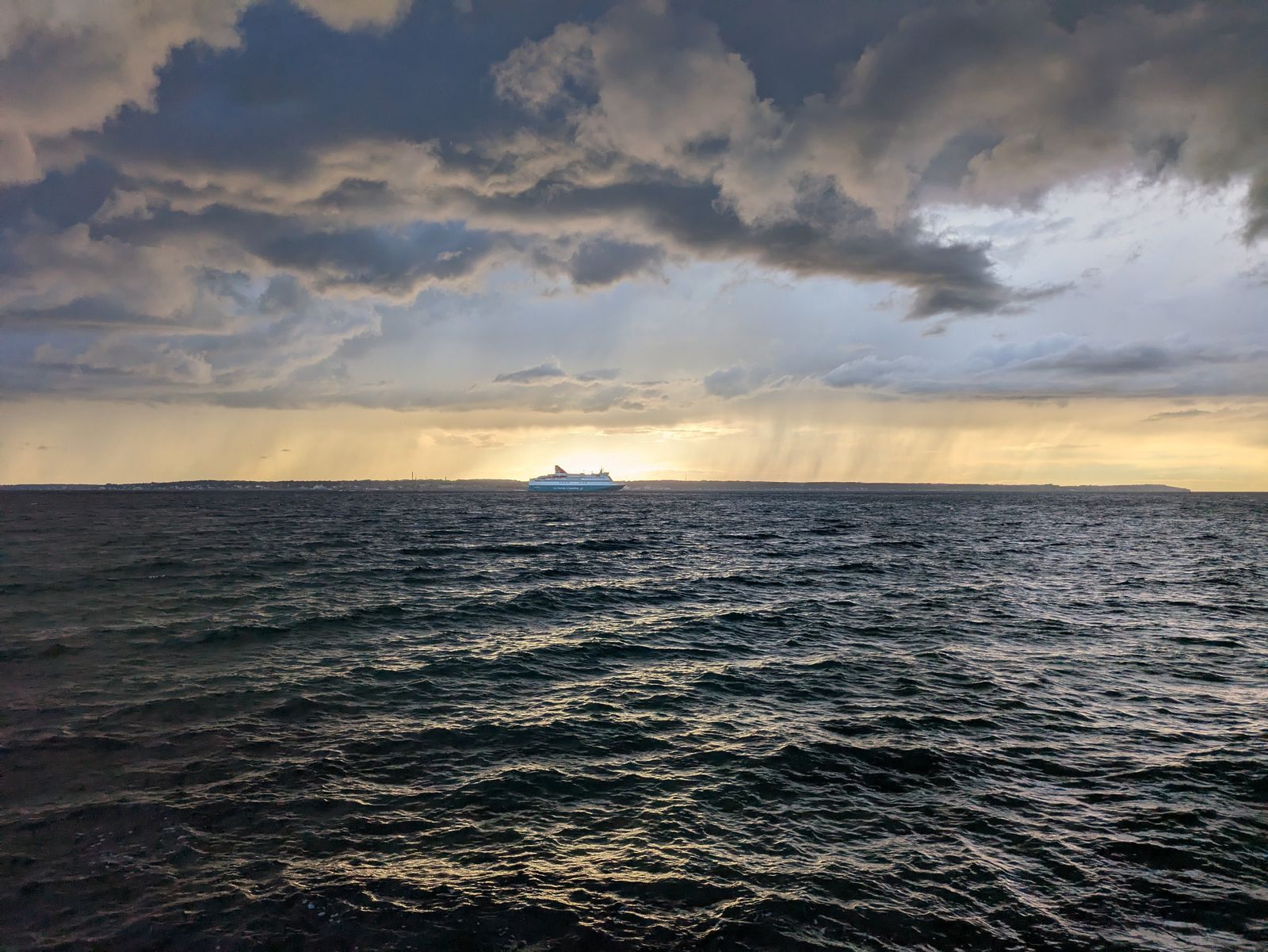 A distant cruise ship on the horizon under dramatic evening clouds, the goal of every cruise vacation planner