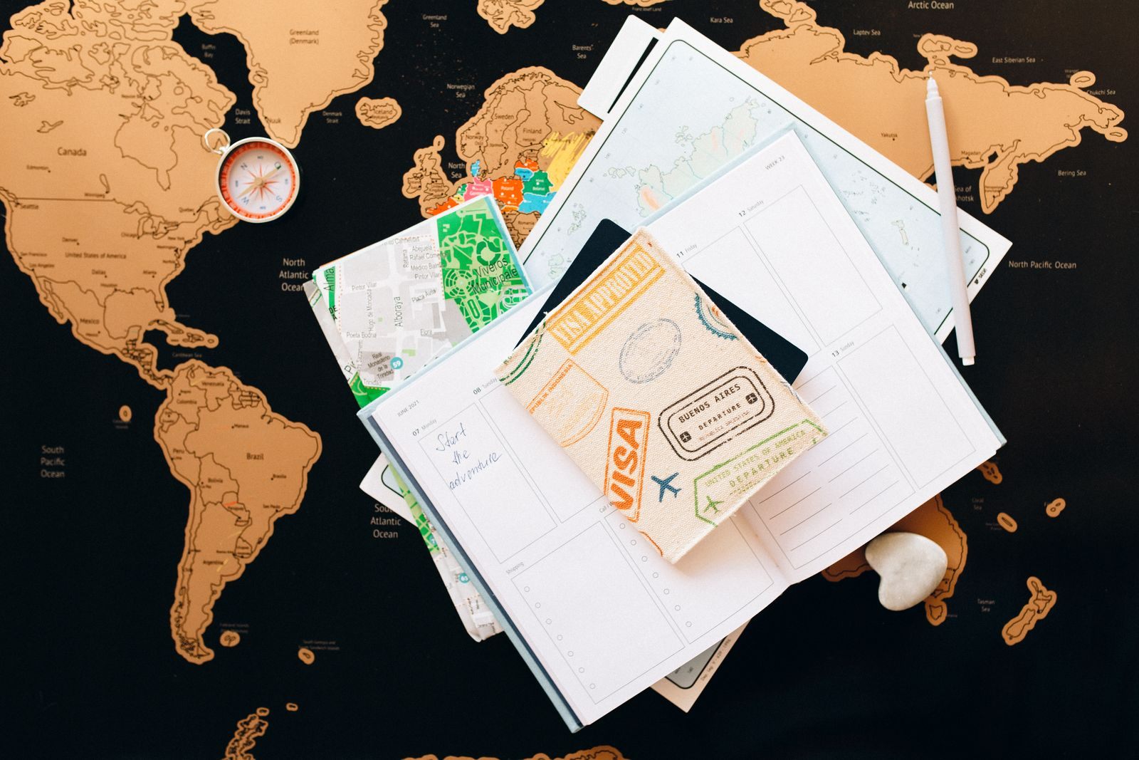 A passport and travel planner spread over a world map, the start of learning how to plan a cruise