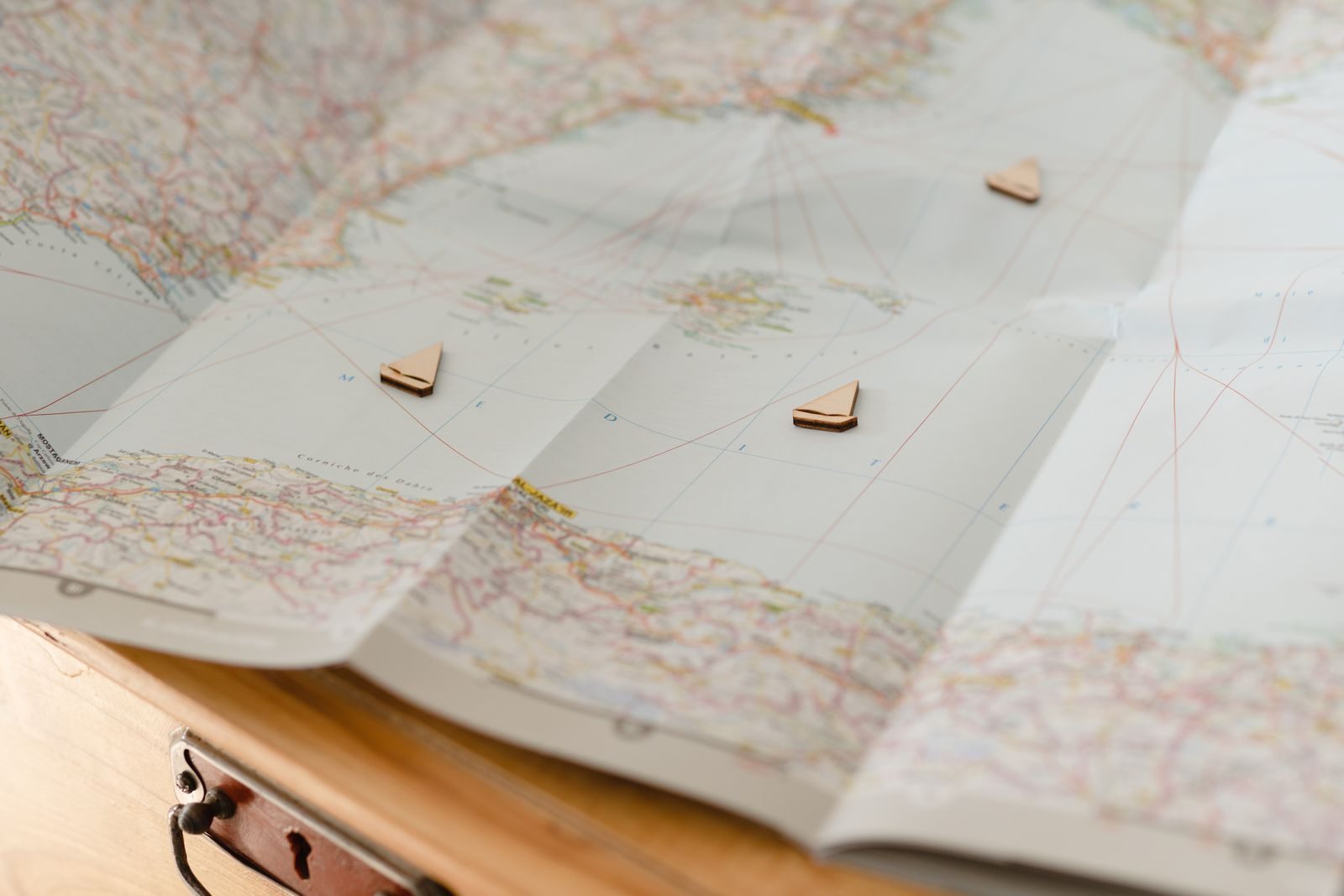 Small wooden ship markers placed on a paper map, choosing the best time to plan a cruise